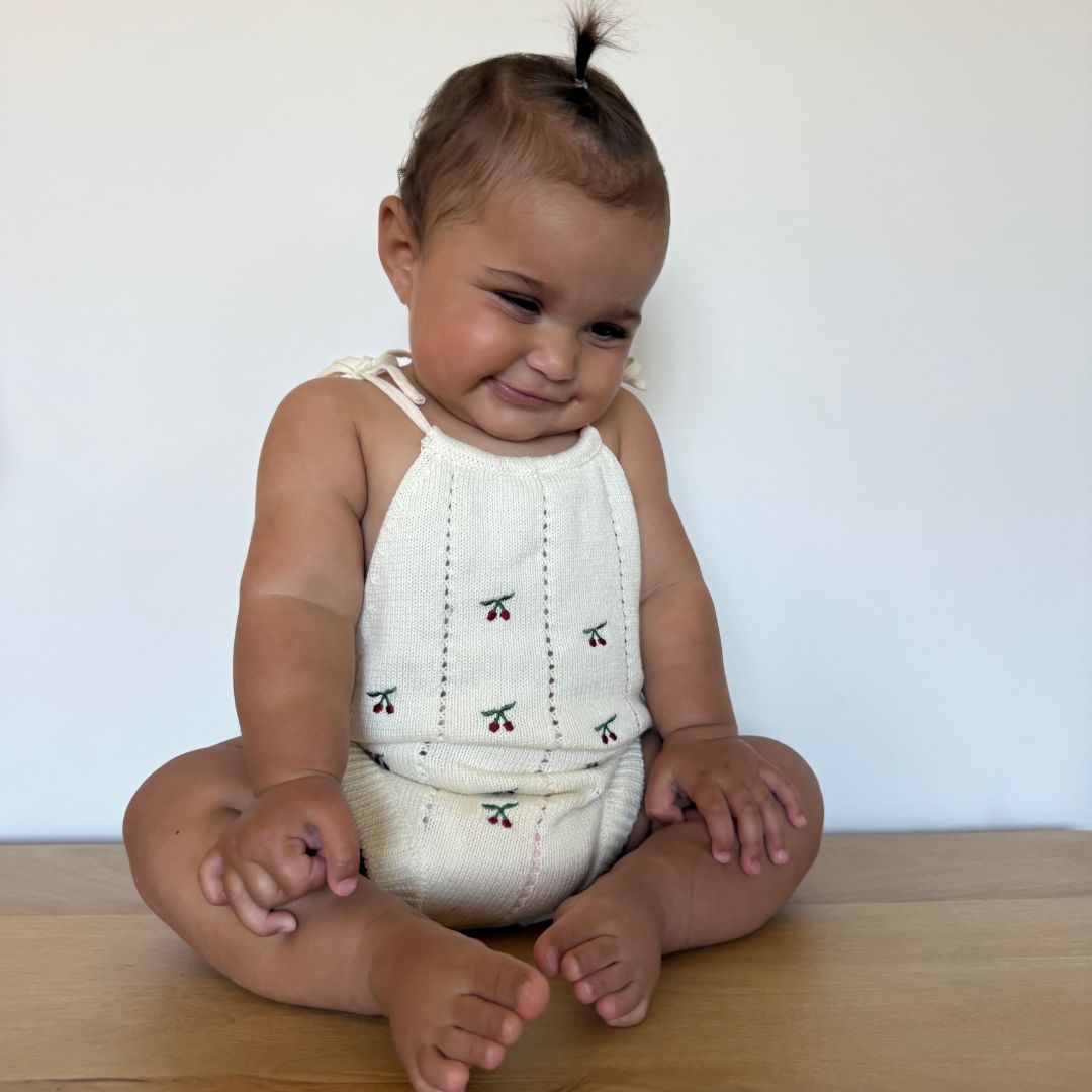 organic cotton romper for babies ages 0 - 24 months. Croquet style romper in beige with Cherry embroided into it front view sitting down