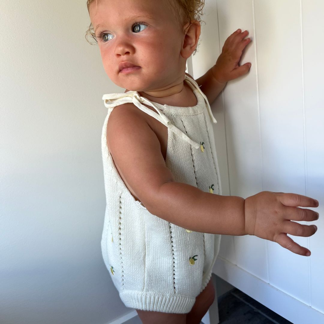 organic cotton romper for babies ages 0 - 24 months. Croquet style romper in beige with lemons embroided into it side view
