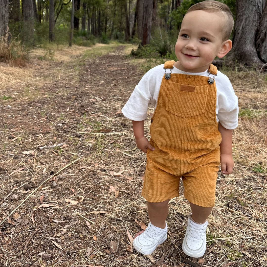 short leg overall, dungaree in colour orange made from organic cotton corduroy clothing for infants, toddlers and kids front view