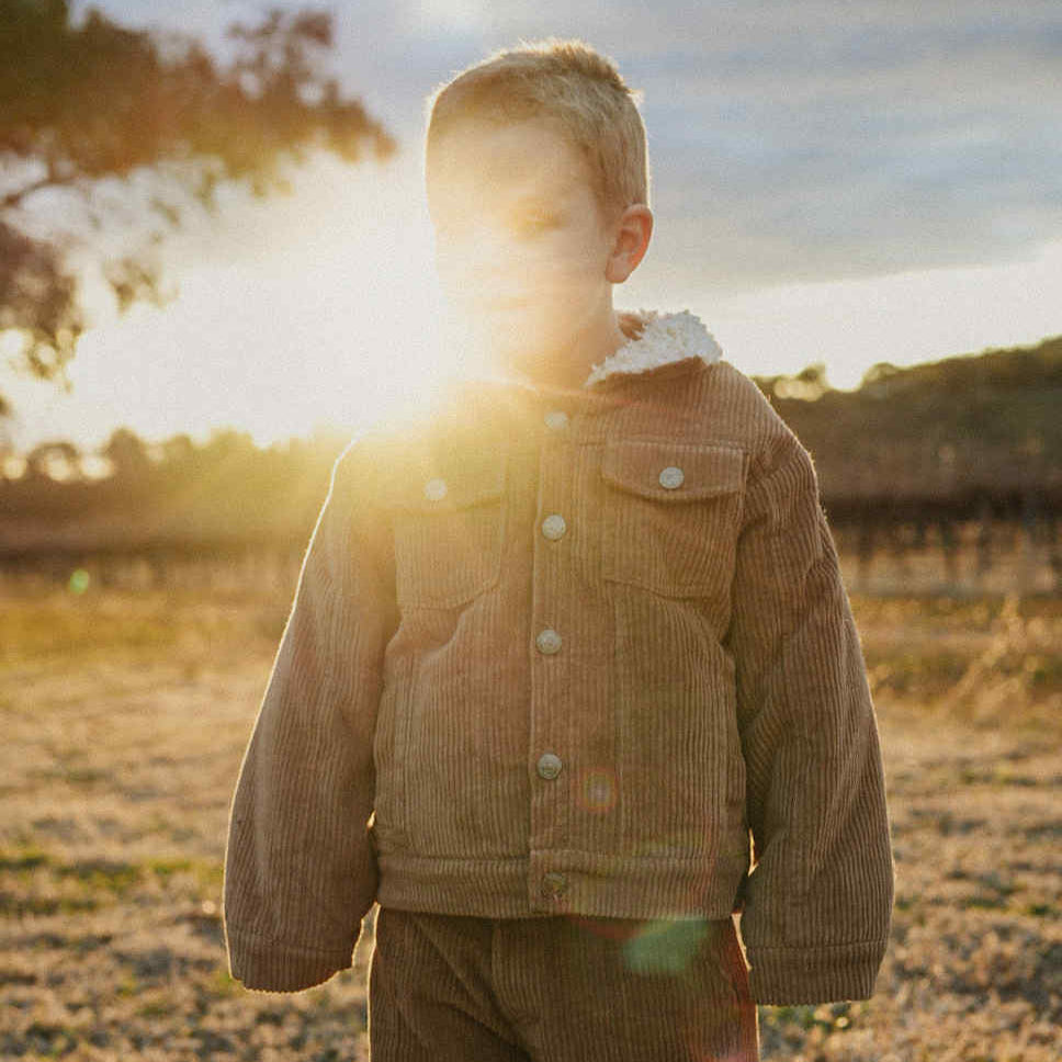 toddler wearing a corduroy jacket with sherpa fleece made from organic cotton close up.