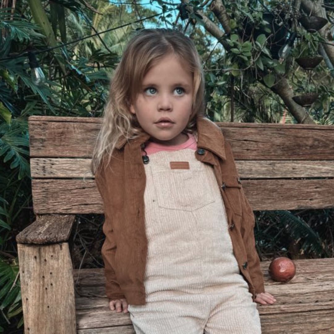 Kids and toddlers chocolate corduroy long sleeve dress shirt and beige corduroy overalls and a passionfruit beside her